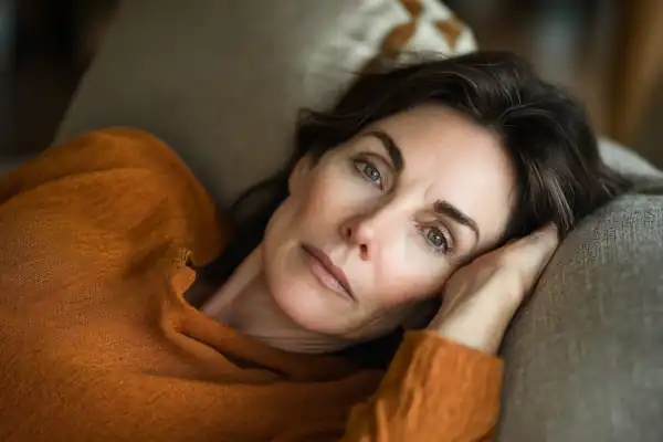 Müde Frau liegt auf der Couch. Sie ist müde, weil sie Probleme mit der Schilddrüse hat